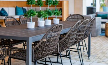 Outdoor dining area with modern wicker chairs and potted plants