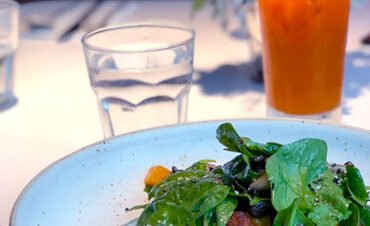 Delicious gourmet plate with grilled chicken, salad, and a refreshing orange drink.