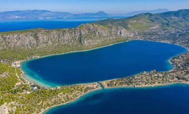 Aerial view of Lake Vouliagmeni with turquoise waters surrounded by mountains near Loutraki
