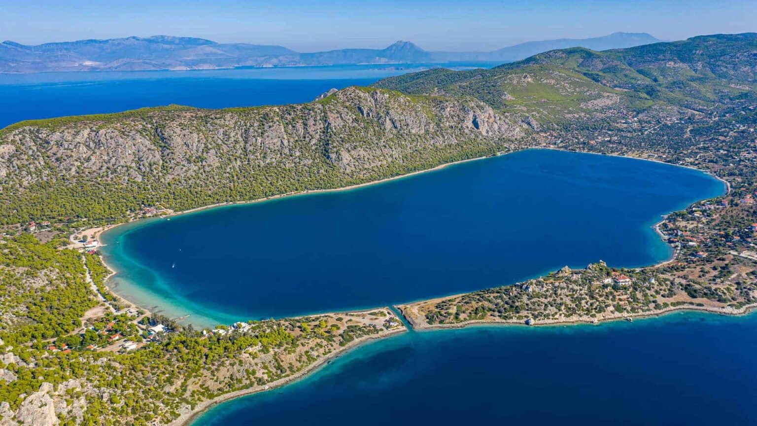 Aerial view of Lake Vouliagmeni with turquoise waters surrounded by mountains near Loutraki